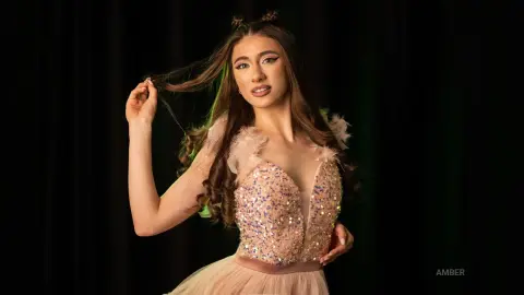 Glamorous woman in a sparkling sequin pink dress posing against a dark studio background.