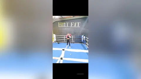 Athletic woman in black workout gear training in a boxing ring at a modern HIT FIT gym.