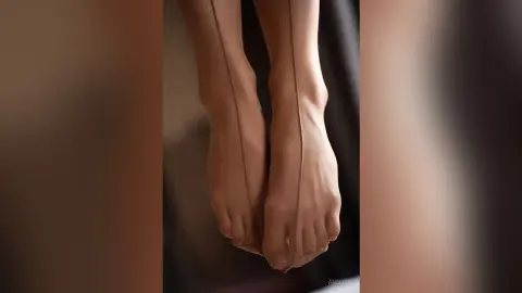 Close-up of feet wearing sheer nude hosiery in a soft, minimalist indoor setting.