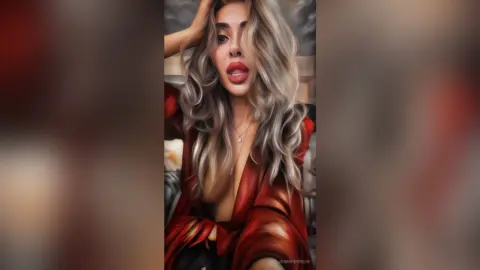 Glamorous woman with wavy blonde hair wearing a red silk blouse in a moody, soft-lit indoor setting.