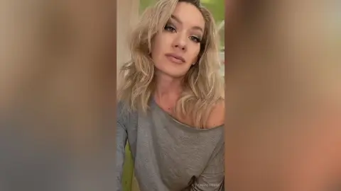 AtlamaDesmond poses with her long blonde hair down, wearing a grey long-sleeved shirt that hangs off one shoulder.
