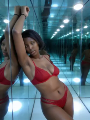 Beautiful Black woman in red lace lingerie posing in a modern mirrored room with cool blue lighting.