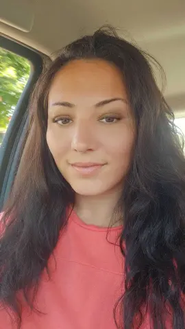 FoxyKara smiling in a pink shirt while sitting in a car.