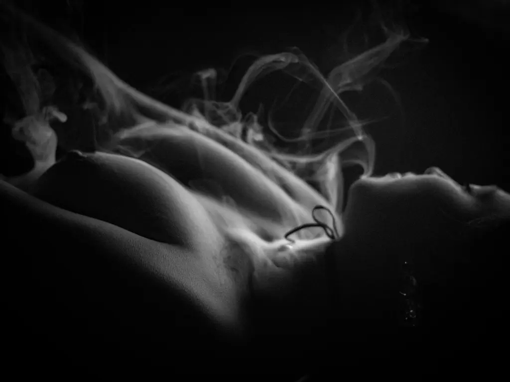 Hade_Beaumontt — Moody black and white artistic photography of a woman's bare torso enveloped in ethereal swirling smoke.