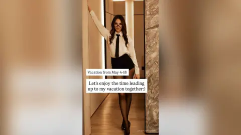 Stylish woman in a white blouse and black skirt posing confidently in a modern minimalist hallway.