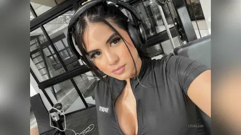 LeiaLein — Young woman with headphones wearing a black athletic top in a modern glass-walled room.