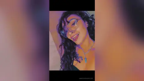 AnoraRockefeller smiles with her tongue out, wearing glasses and a silver necklace against a plain background.