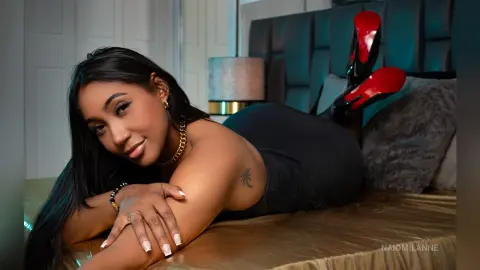 Beautiful woman in a black dress lying on a bed in a moody, elegant bedroom setting.