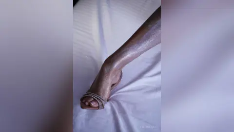 FelishaRose shows off her smooth, shimmering skin and toes while wearing silver strappy sandals on a white bedsheet.