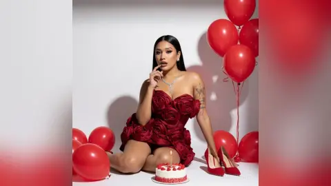 LaurenKaterine poses in a red rose-style strapless dress and red heels, surrounded by red balloons and a small birthday cake.