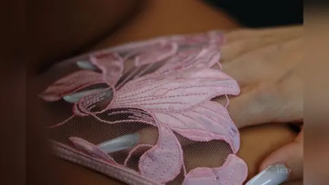 Close-up of a woman wearing elegant pink floral lace gloves for a romantic and feminine aesthetic.