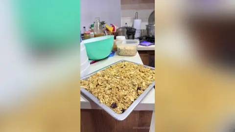 Homemade granola clusters on a baking sheet in a bright kitchen setting.