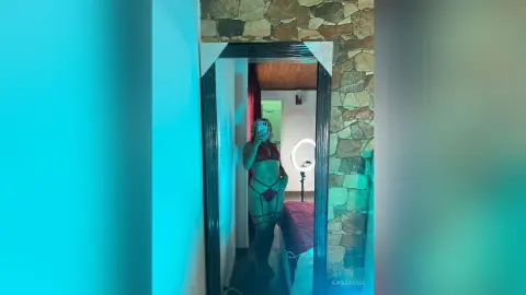 Young woman in red lingerie taking a mirror selfie in a modern bedroom with teal mood lighting.