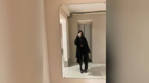 AndreaHazel stands in front of a mirror wearing a black long-sleeved top and black pants.