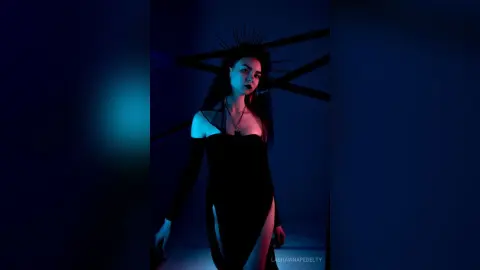Moody portrait of a woman in a black off-the-shoulder dress against a dark blue cinematic background.