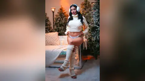 Aleja poses in a white cropped turtleneck sweater and white lace panties, wearing white furry earmuffs and leg warmers.