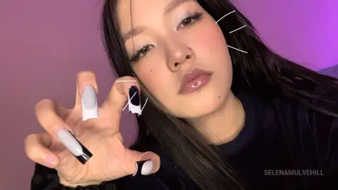 Young woman with long dark hair and long white French tip nails posing in soft purple lighting.