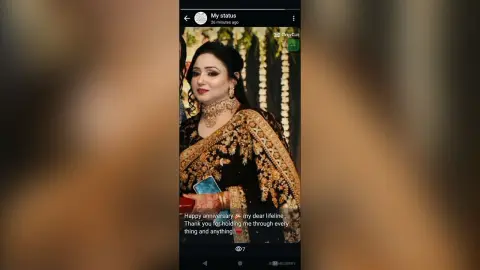 Elegant woman in traditional gold embroidered black lehenga posing for a celebratory anniversary portrait.