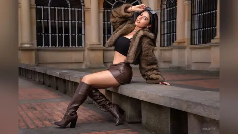 Stylish woman in a brown faux fur jacket and leather shorts posing outdoors in a classic urban setting.
