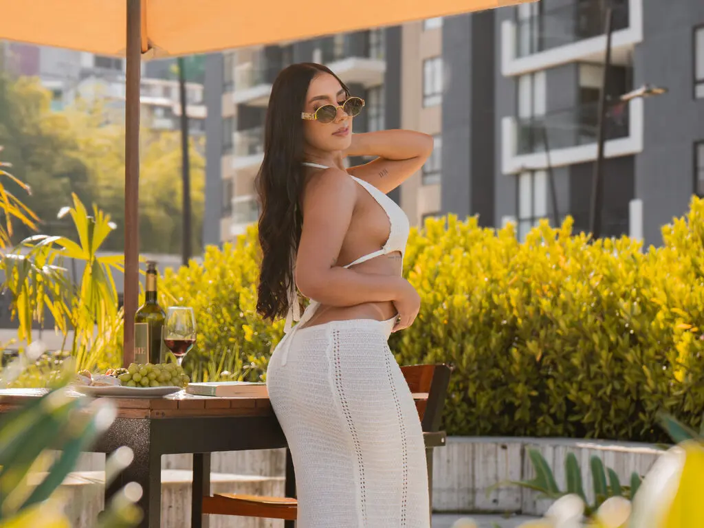 Stylish woman in a white crochet bikini and sunglasses relaxing at an outdoor cafe table with wine.