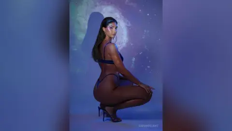 Athletic woman in a blue bikini posing in moody blue studio lighting.
