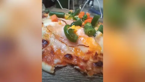 Delicious homemade pizza topped with melted cheese, green peppers, and fresh tomato chunks on a wooden board.