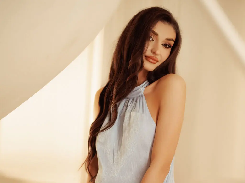 Elegant woman in a light blue halter top posing in warm sunlight for a soft, glamorous portrait.
