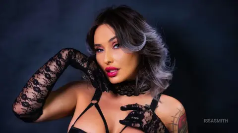 Glamorous woman in black lace gloves and lingerie posing against a dark moody background.