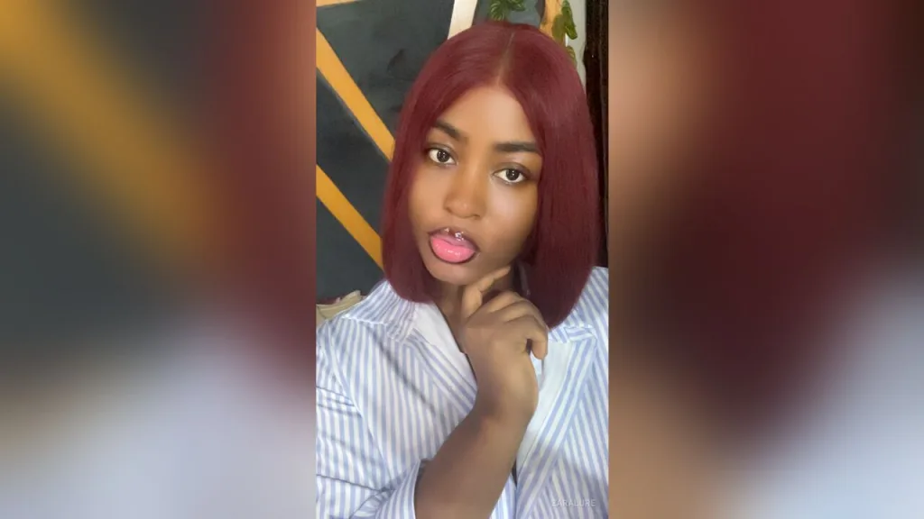 ZaraLure — ZaraLure with red hair poses in a blue and white striped shirt while looking at the camera.