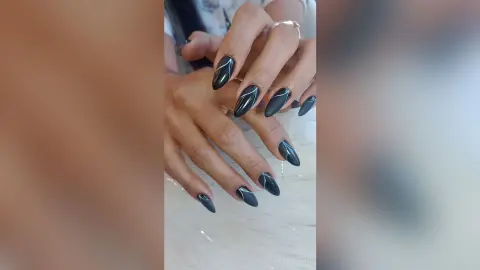 Close-up of elegant long black almond nails with minimalist white swirl nail art design.