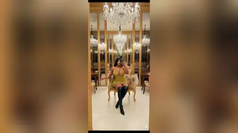Elegant woman in a gold cocktail dress and black thigh-high boots sitting in a luxury gold-accented room.