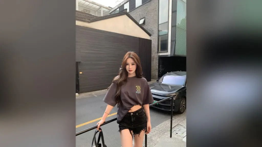 XiaoJuan — XiaoJuan stands outdoors wearing a brown t-shirt and black denim shorts, looking at the camera with long brown hair.