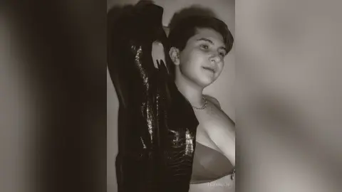 Moody black and white portrait of a young woman wearing a textured leather jacket and silver necklace.
