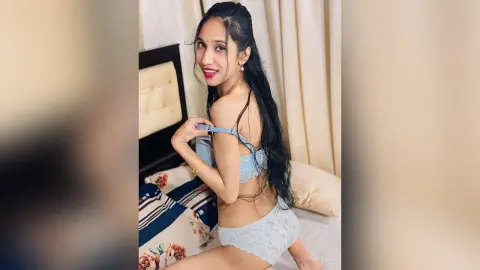 ErinKings poses on a bed wearing a light blue lace bra and matching panties, showing her back and long black hair.