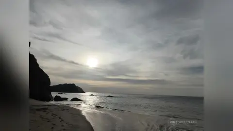Moody seascape view of a cloudy sky over a calm ocean beach at dusk.