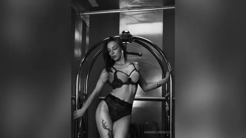 Moody black and white portrait of a woman in lace lingerie posing in a modern metallic studio setting.