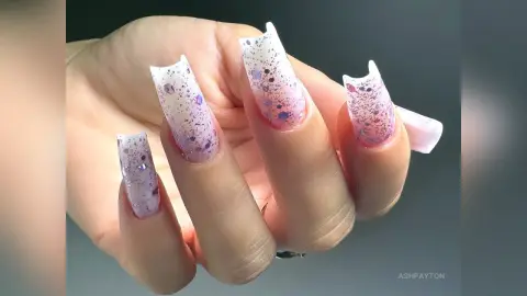 Close-up of long coffin-shaped nails with lavender glitter and iridescent sparkle finish.