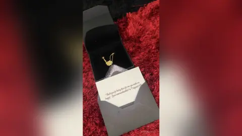 DayanaHille's gold necklace rests inside a black velvet jewelry box next to a white card.