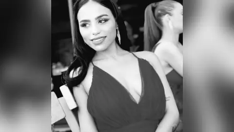 Elegant woman in a black V-neck dress posing with a sophisticated mood in a black and white portrait.
