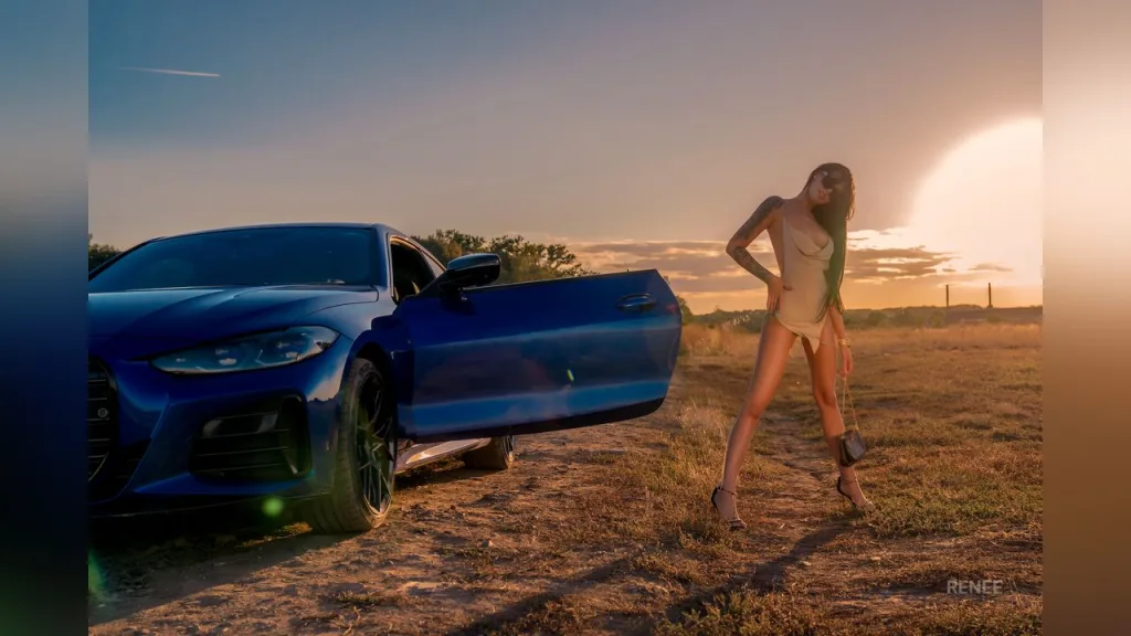Nude woman posing in a car interior against a clear blue sky during a sunny outdoor photoshoot.