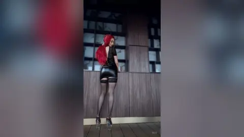 Red-haired woman in a black leather mini dress and sheer tights posing on a modern wooden balcony at dusk.