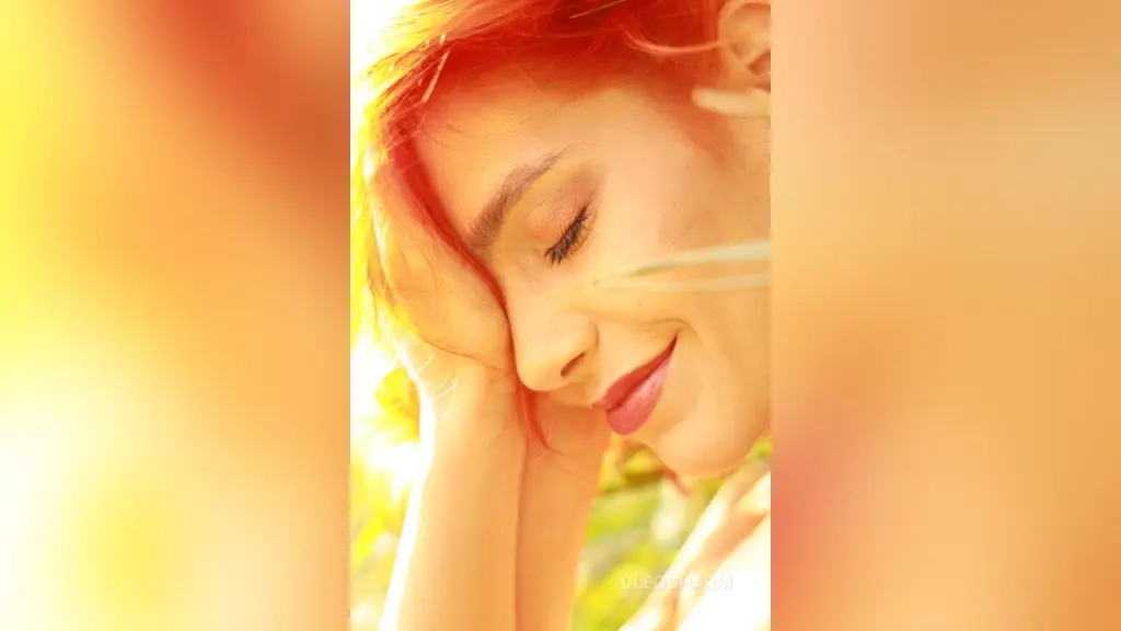 Close-up portrait of a blonde woman with glamorous makeup and gold statement earrings in soft indoor lighting.