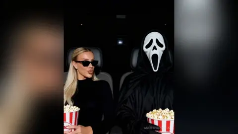 Blonde woman in black sunglasses and a person in a Scream Ghostface costume sharing popcorn in a dark theater.