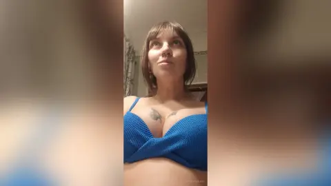 StacyMalvin wearing a blue knit bikini top, looking up with her brown hair styled in a bob with bangs.