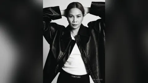 MilaSwan — MilaSwan poses with her hands behind her head wearing an open black leather jacket and a white top.