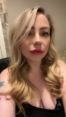 FrankiiRayeXXXX poses with long blonde hair and red lipstick, wearing a black tank top that shows her cleavage.