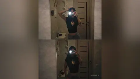 SofiMils poses for a mirror selfie wearing a black tank top and denim shorts, holding her phone up to her face in a dimly lit room.
