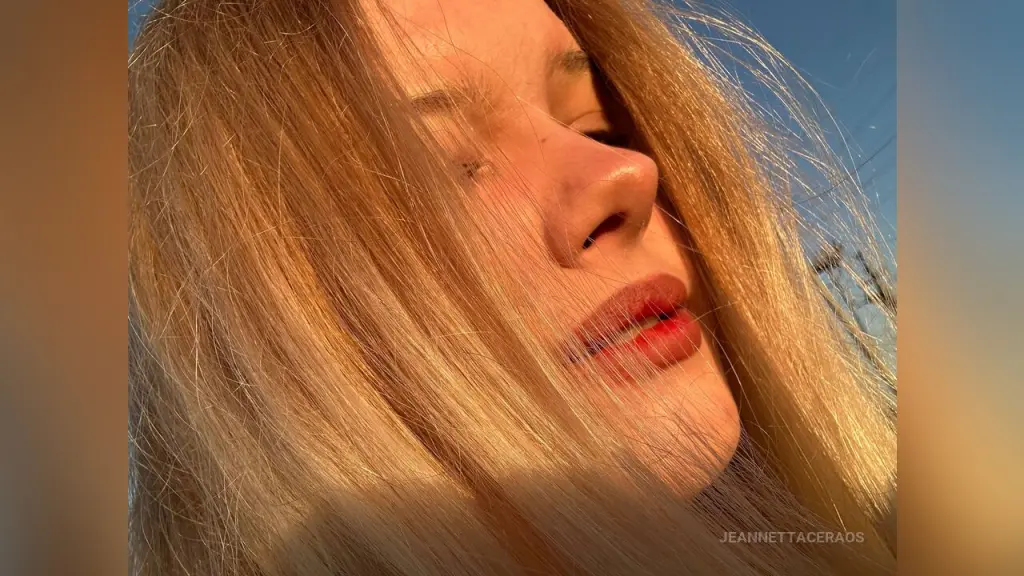 Close-up portrait of a blonde girl with freckles looking at the camera in a bright indoor setting.