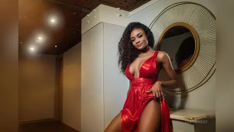 Elegant woman in a glamorous red evening gown posing in a modern luxury hallway.