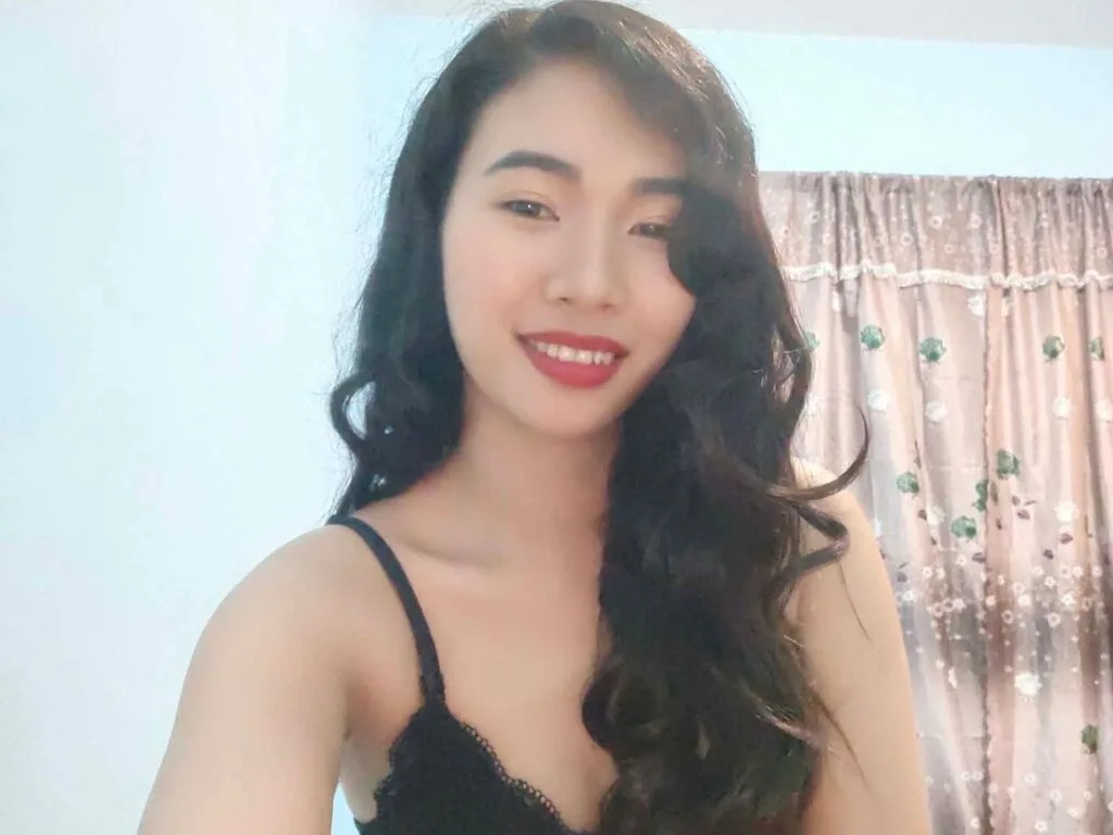 AndreaCapan — AndreaCapan smiles while wearing a black lace camisole with her long dark hair styled in waves.